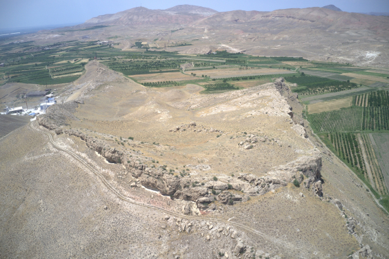 This drone photograph faces northwest over the Vedi Fortress site. Cliffs surround and protect much of the site, with two lines of fortress walls protecting the western approach to the citadel.